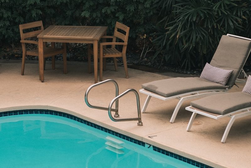 two gray sunbathing loungers beside pool